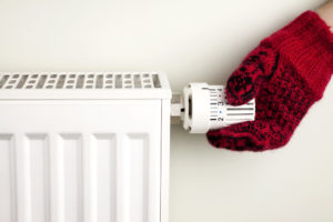 A hand with a red glove adjusting the setting on a white heating unit
