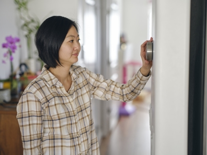 woman adjusting thermostat