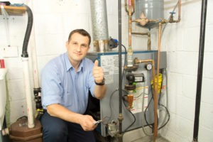 A Lubbock HVAC technician in a blue shirt giving a thumbs up after installing a furnace