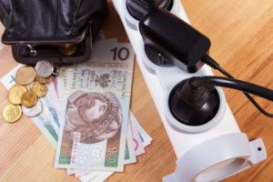 A power strip and a black coin purse with non-US dollars and coins next to it