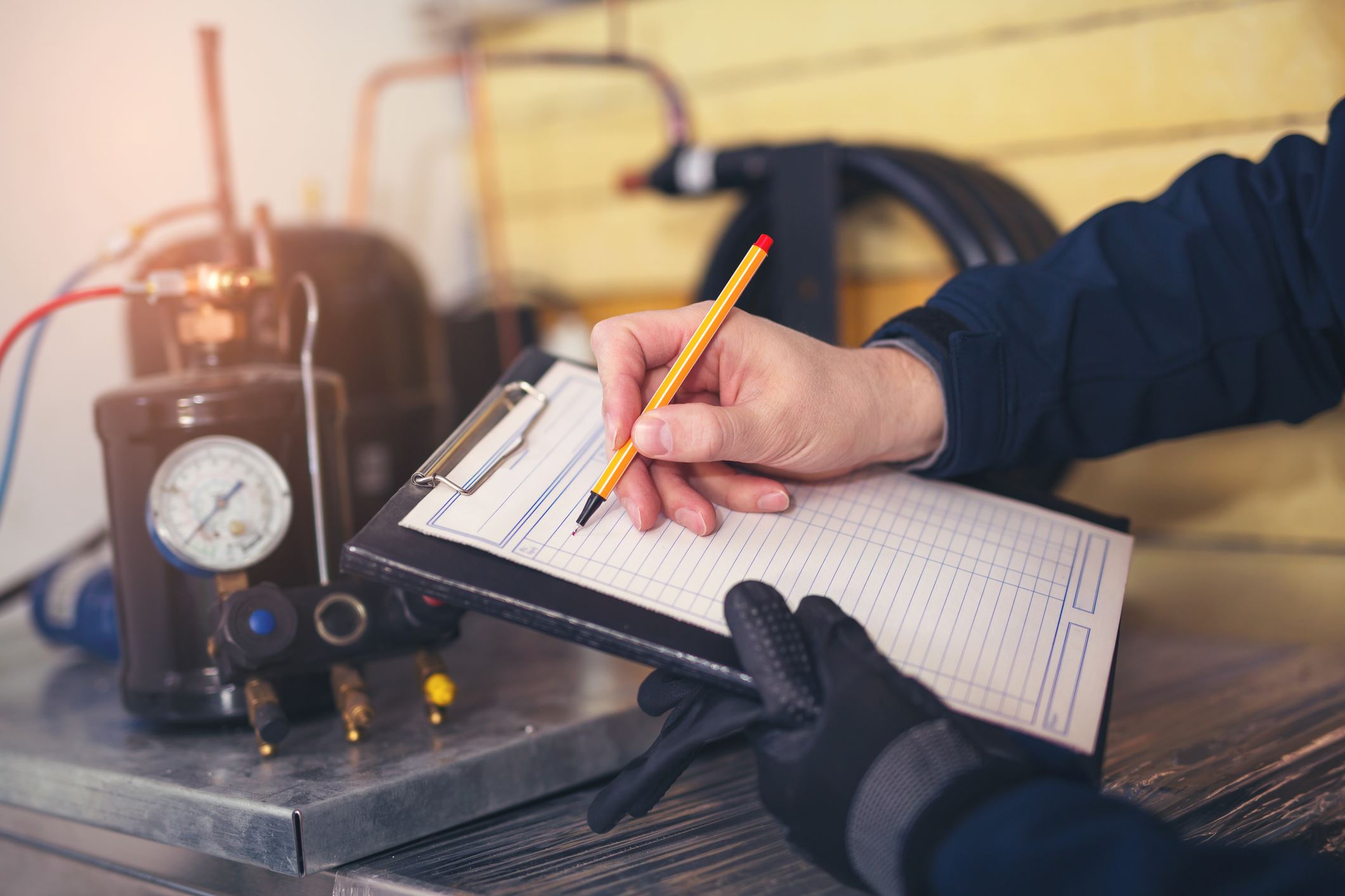 A Lubbock HVAC technician taking notes on a clipboard with HVAC parts on a counter