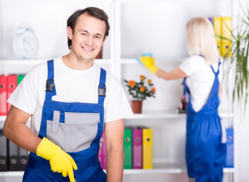 a brunette man and a blonde woman in blue work overalls cleaning their home