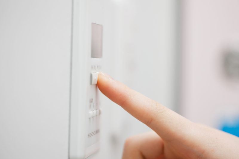  A person pressing the button to use the voice control and set the temperature of the thermostat