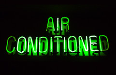 A green neon sign that says, "Air Conditioned"