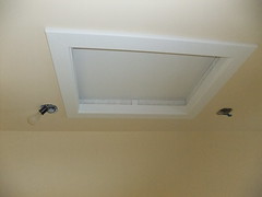 Attic access with white casing on a beige ceiling