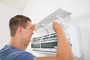 A man changing the air filter in a ductless unit